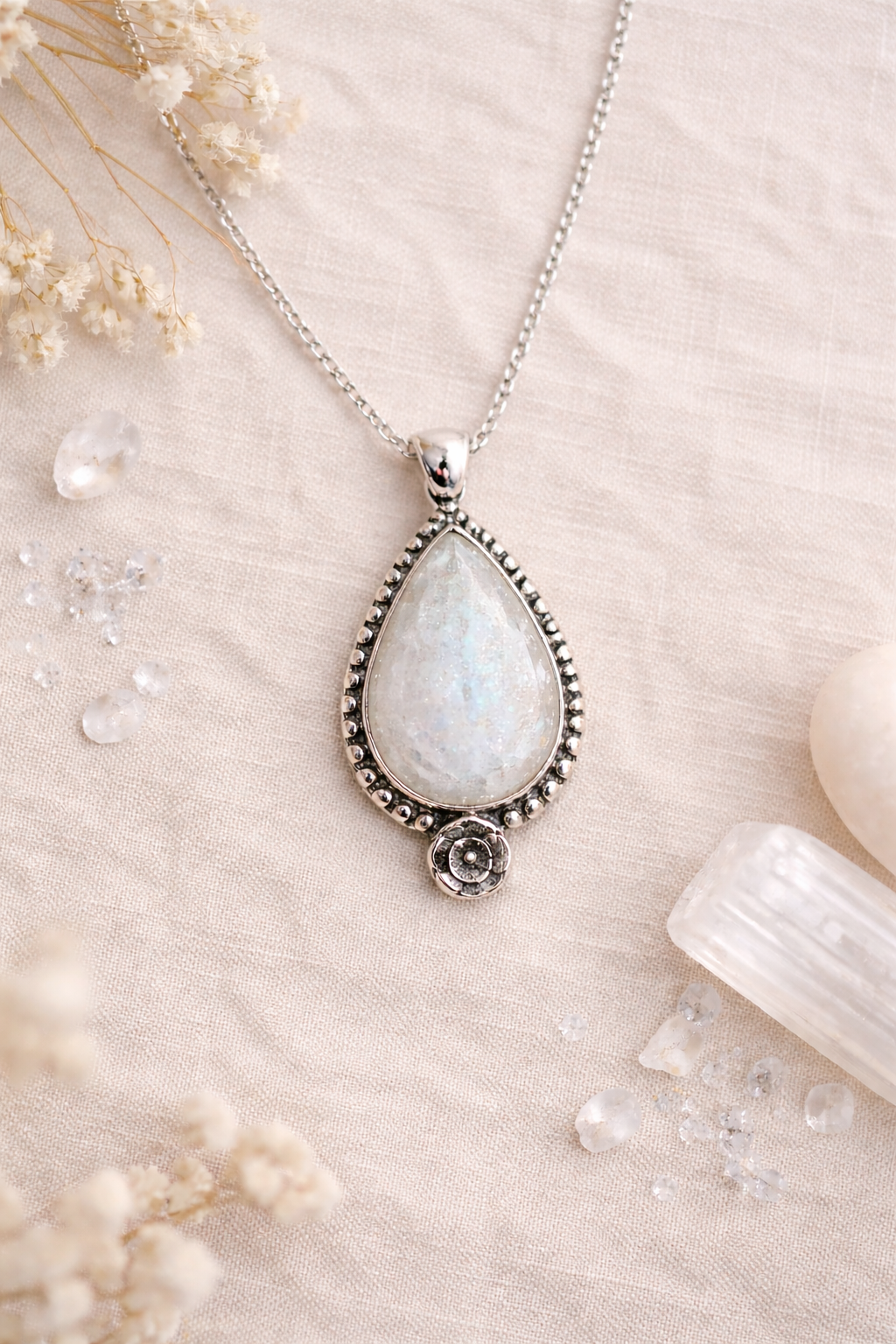 Teardrop-shaped Moonstone pendant necklace with a white stone on a neutral background