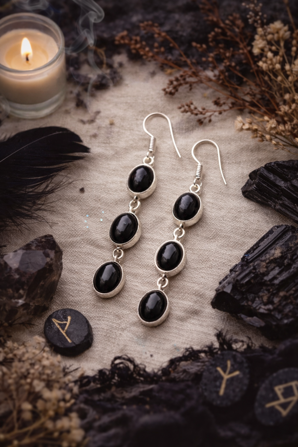 Black Onyx stone earrings on a surface with candles and crystals