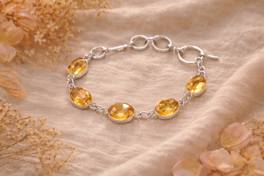 Silver bracelet with yellow citrine gemstones on a soft beige background