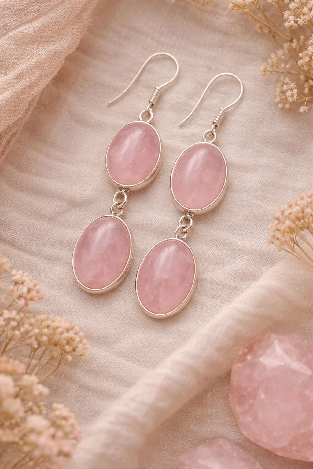 Pink rose quartz stone earrings on a soft beige background with flowers.