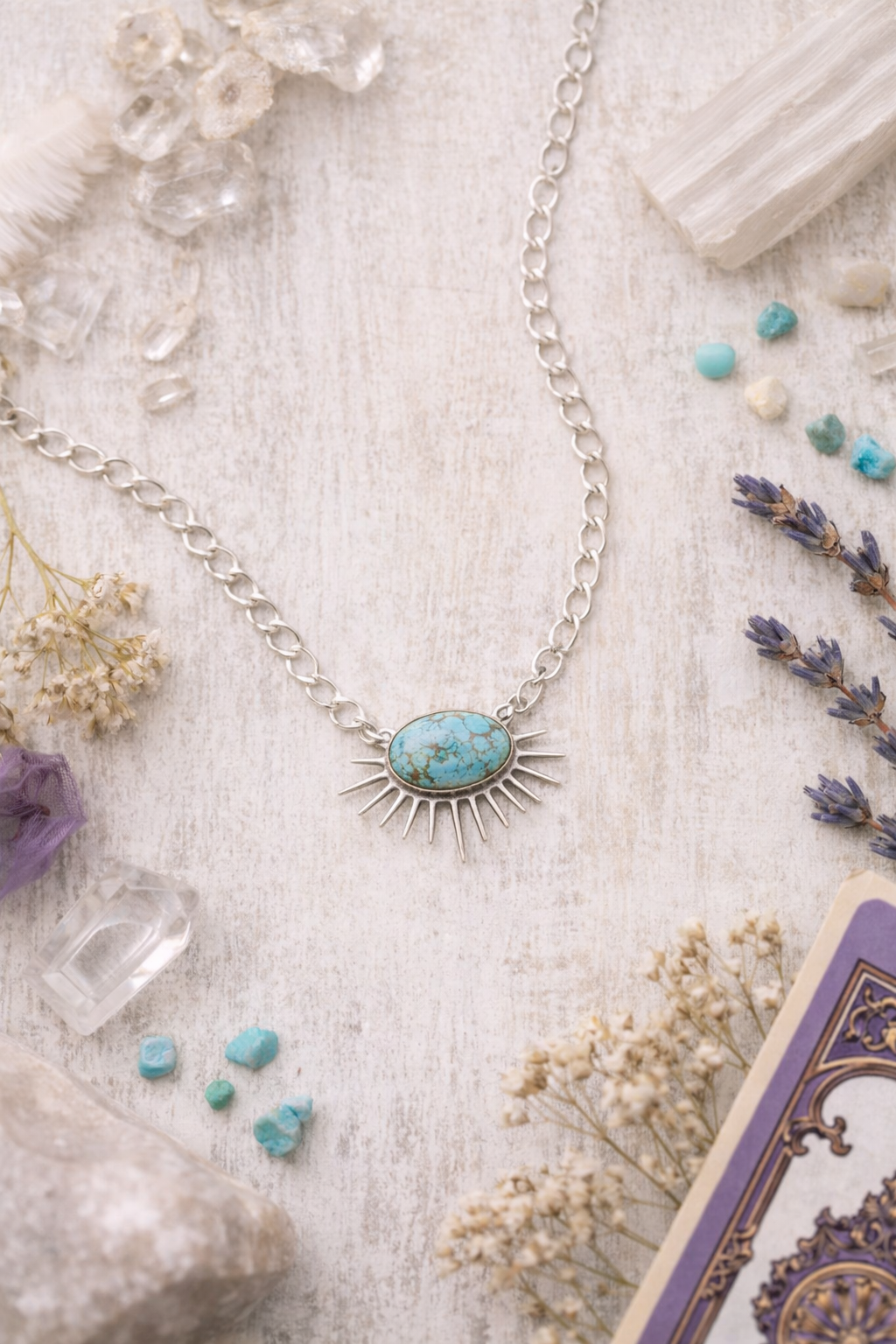 turquoise sun shaped pendant on white background with crystals and flowers