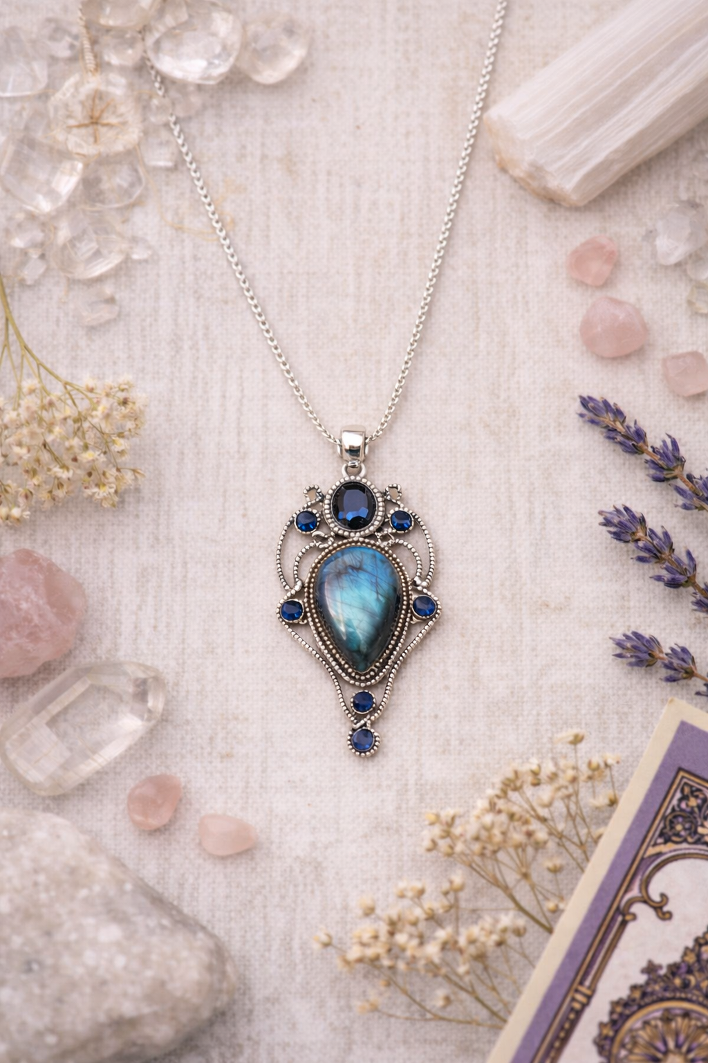 large labradorite pendant on white background with crystals and dried lavender