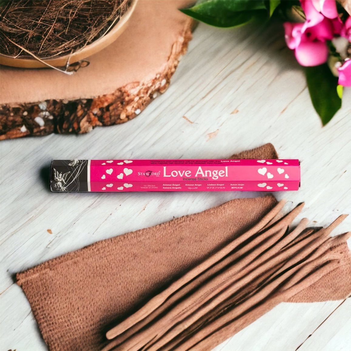 A package of Love Angel brand incense sticks with a pink and brown design, accompanied by a group of brown incense sticks laid out on a wooden surface.