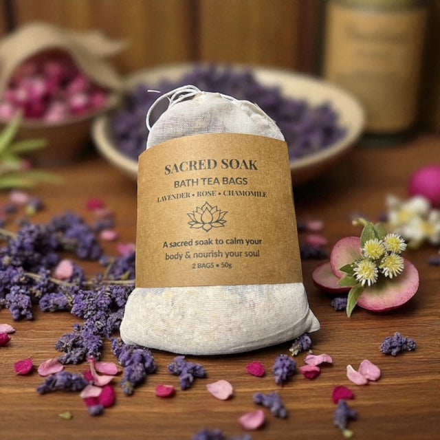 Sacred Soap bath tea bags on a wooden surface with flowers and a bowl in the background