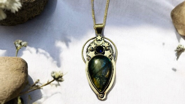 Labradorite pendant with a blue gemstone on a white background