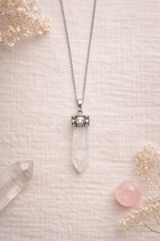 clear quartz wand  pendant necklace on a textured surface with dried flowers
