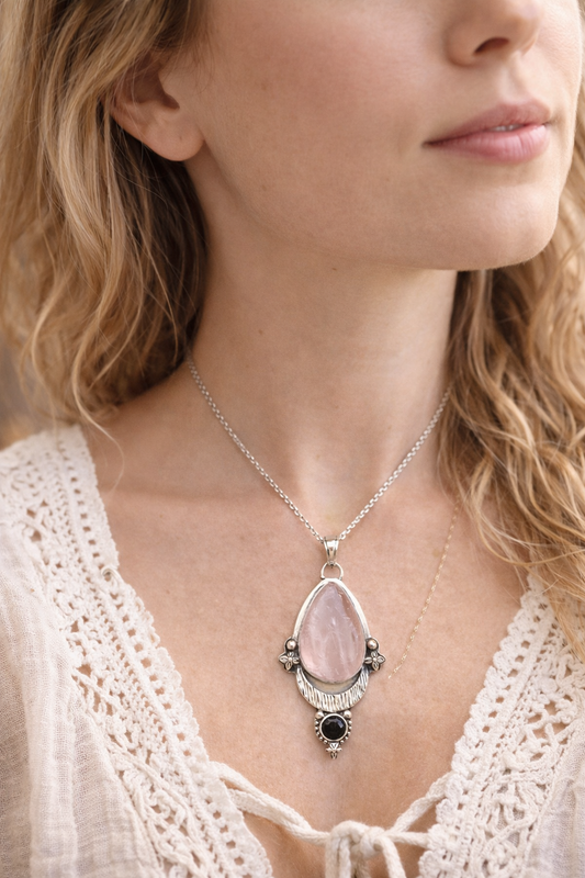 Necklace with a pink rose quartz teardrop pendant worn by a person