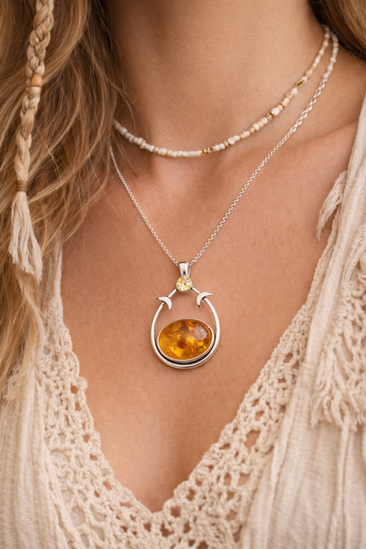 Necklace with a pendant featuring amber stone worn by a person with braided hair.