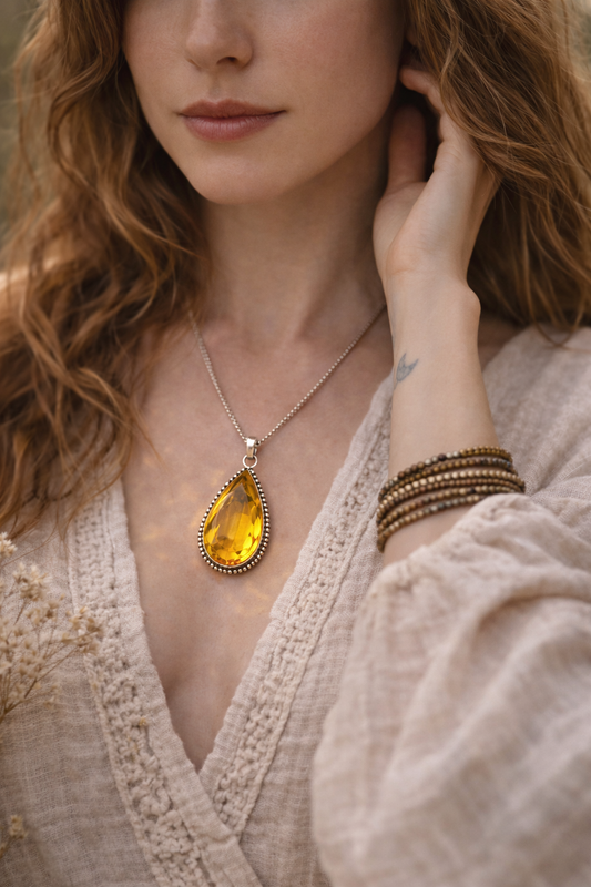 Woman wearing a yellow citrine teardrop pendant necklace and bracelets.