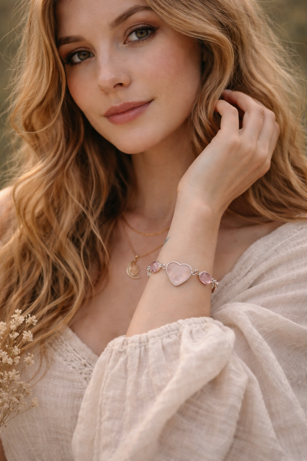 Woman wearing a heart-shaped  rose quartz bracelet with a blurred natural background