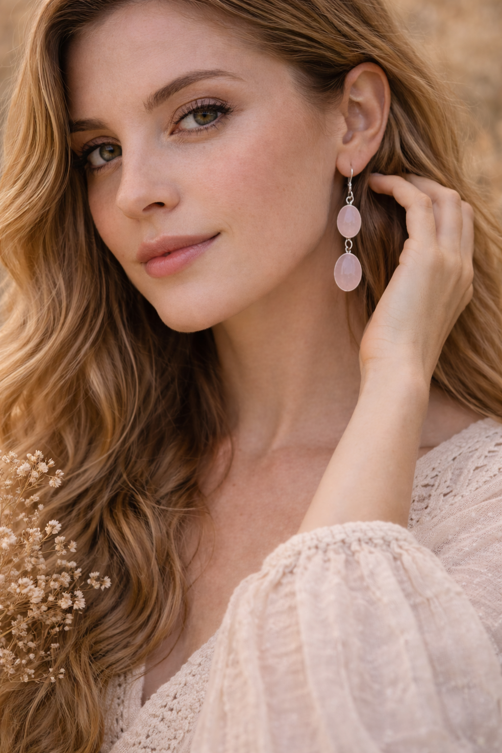 Woman wearing pink  rose quartz earrings outdoors with a blurred natural background
