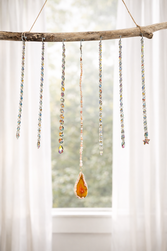 Decorative hanging suncatcher with Ab Crystals and a teardrop-shaped orange agate slice against a blurred natural background.