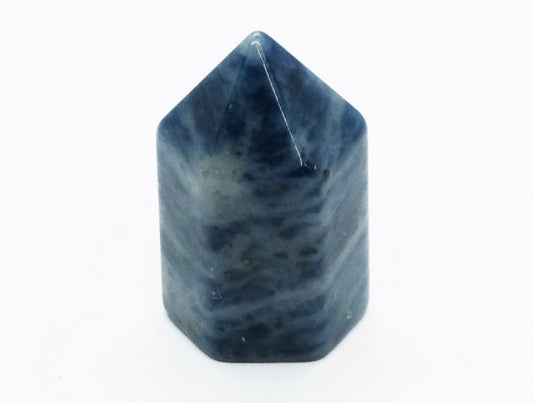 A mini sodalite crystal point with a deep blue color and white calming patterns.