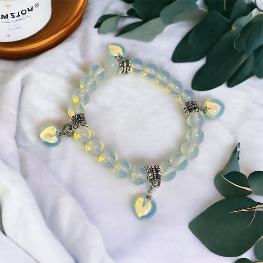 A bracelet with a series of opalite beads and four Opalite heart-shaped charms, featuring silver accents 