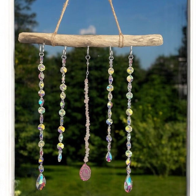 Decorative sun catcher with pink agate slice and crystals on a natural background